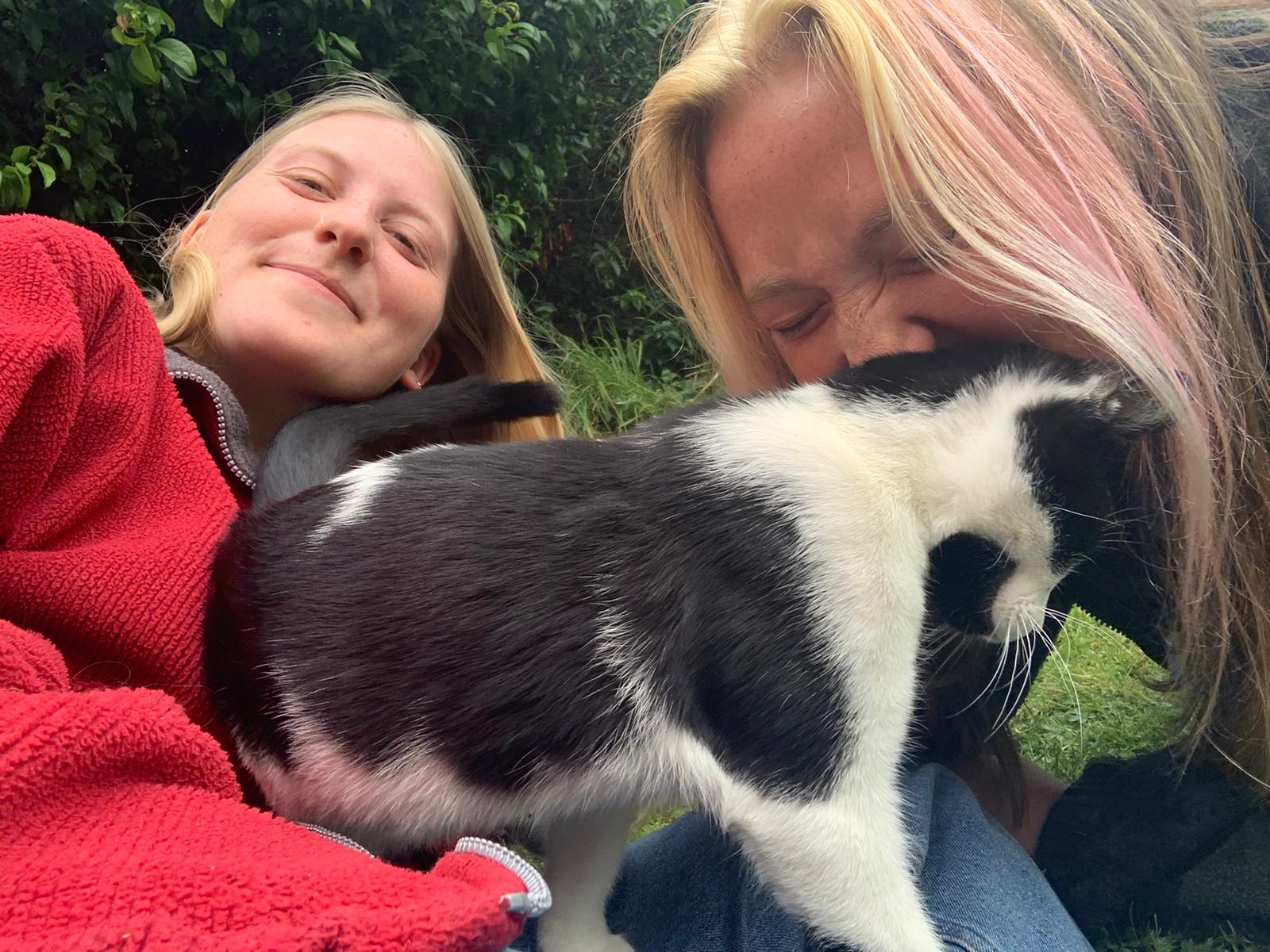 Two women and a black and white cat.